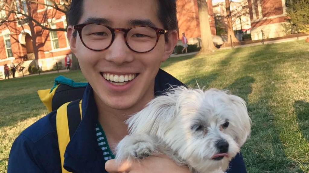 Sean Wu smiling and holding his small dog